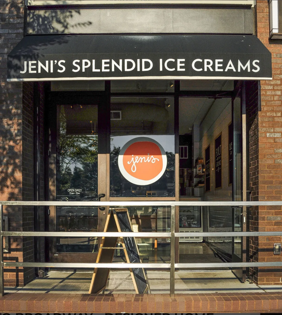 A close-up of Jeni’s Splendid Ice Creams' storefront, featuring bright signage, a welcoming glass entrance, and a menu board. The cheerful ambiance and promise of sweet treats highlight one of the area's must-visit destinations.