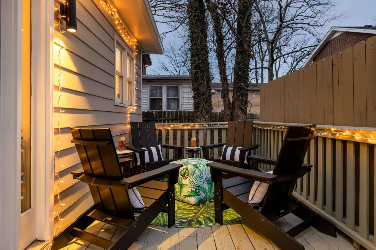 A welcoming deck with wooden chairs, string lights, a colorful cushion, and deck flooring, creating a relaxed and celebratory atmosphere. The setup suggests opportunities for evening drinks, storytelling, and making memories under the stars.