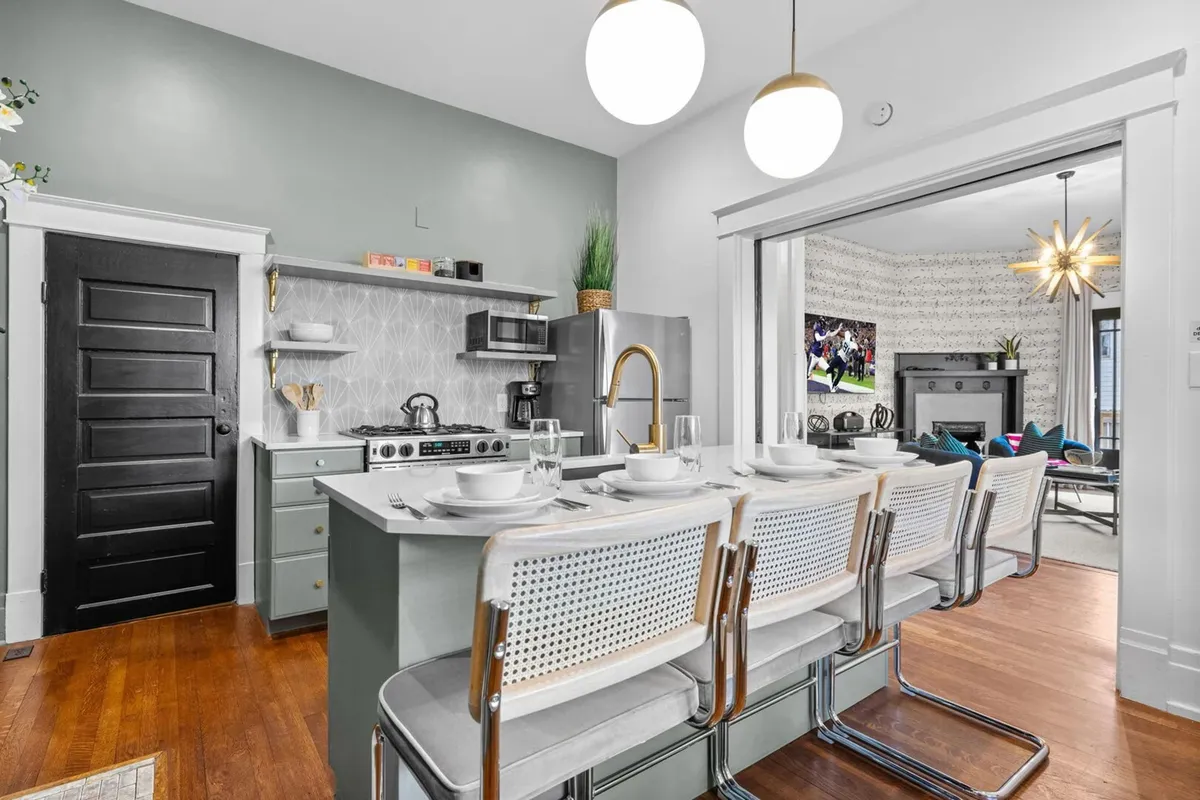 The photo captures a stylish, open-plan kitchen with a large island featuring bar seating, modern stainless steel appliances, and seamless flow into the adjacent living area. Decorative touches and ample workspace make it ideal for cooking and social gatherings.